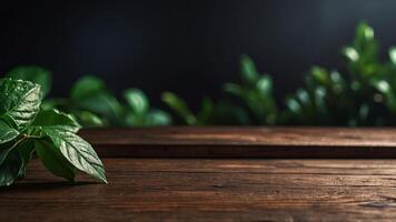Wooden table top on blurred dark background with green leaves. Banner with copy space. Template showcase scene for display, montage, advertising product. photo