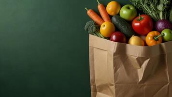 Paper bag with healthy vegetables and fruits on a green background. Banner with copy space, top view. Culinary background with vegetarian food photo