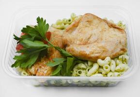 Fried chicken fillet with a side dish of pasta. Delicious meat breakfast in a container. photo