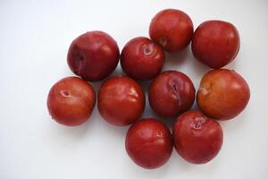 Red plums on a white background. Plums on a plate. Washed fruits. photo