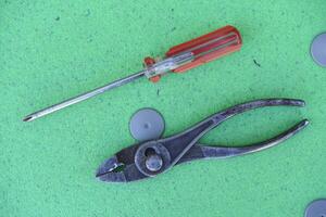 Pliers and a screwdriver on a green background. Tools. photo