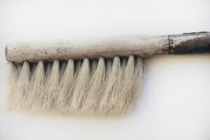 An old brush with a wooden handle on a white background. An old detail. photo