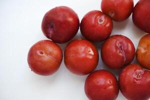 Red plums on a white background. Plums on a plate. Washed fruits. photo