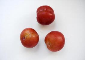Red plums on a white background. Plums on a plate. Washed fruits. photo