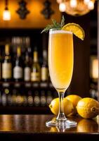 A delicious Mimosa cocktail drink on a polished Mahogany bar top in a cozy bar with various alcohol bottles out of focus in the background. photo