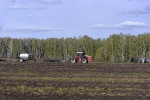 Agricultural machines for sowing grain in the field. Red tractors in the sowing campaign. photo