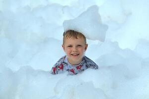 happy little boy with foam on his head, in wet clothes at a foam party photo
