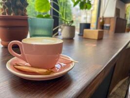Cappuccino coffee cup at cafe table. Closeup of rosetta flower drawing in foam. photo