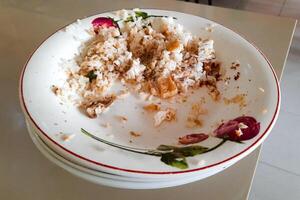 Top view of an unfinished meal on a ceramic plate on the table at a restaurant. Leftover food on plate photo