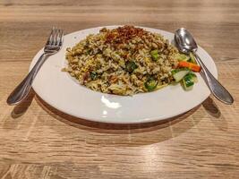 table manner a plate of fried rice on a wooden table with a spoon on the right and a fork on the left of the plate photo
