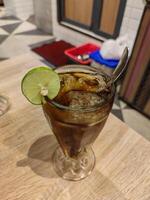 a glass of lemon tea cocktail garnished with a slice of lime at a fancy restaurant photo