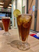 a glass of lemon tea cocktail garnished with a slice of lime at a fancy restaurant photo