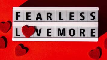 Lightbox with text FEAR LESS LOVE MORE. Motivational Words Quotes Concept with red hearts. Colorful red background. Minimalistic creative concept. Inspirational phrase video