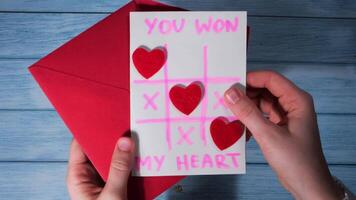 Opening making envelope with card for Valentines Day. Text YOU WON MY HEART and tic tac toe game Postcard craft, greeting card. Handmade Valentine greeting card gift with your own hands video
