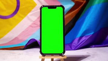 Zoom in out Mobile phone with chroma key on Rainbow LGBTQIA flag made from silk material background. Happy pride month. Symbol of LGBTQ pride month. Equal rights. Peace and freedom. Support LGBTQIA community. Diversity equality video