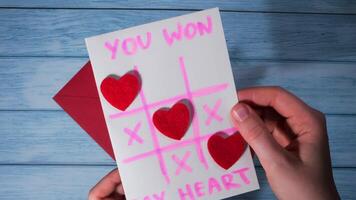 Opening making envelope with card for Valentines Day. Text YOU WON MY HEART and tic tac toe game Postcard craft, greeting card. Handmade Valentine greeting card gift with your own hands video