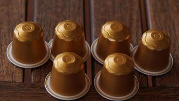 a group of six golden coffee capsules sitting on top of a wooden table photo