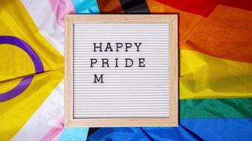 Stop motion HAPPY PRIDE MONTH frame on Rainbow LGBTQIA flag made from silk material. Symbol of LGBTQ pride month. Equal rights. Peace and freedom. Support LGBTQIA community. Diversity equality video