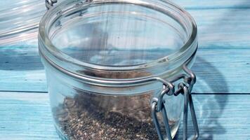 Slow motion chia seeds fall in glass jar. Healthy superfood rich in Omega 3 fatty acids. Dry healthy natural ingredient. Chia grains are falling. Vegetarian food video