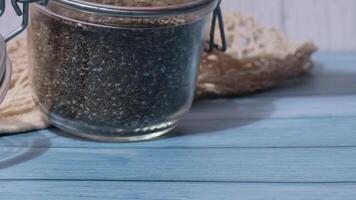 Slow motion chia seeds fall from glass jar. Healthy superfood rich in Omega 3 fatty acids. Dry healthy natural ingredient. Chia grains are falling. Vegetarian food video