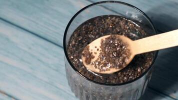 Preparing superfood water drink rich in Omega 3 fatty acids. Pouring coconut water. Adding soaked chia seeds and lemon detox Breakfast. Clean eating, weight loss, dieting food concept Vegetarian Healthy cooking process video