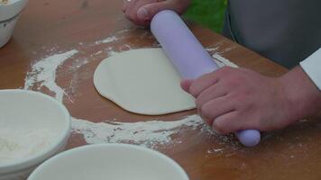 Closeup shot of baker hands rolls dough in flour on table with a rolling pin video