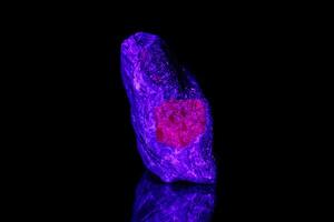 macro mineral stone ruby under ultraviolet light on a black background photo