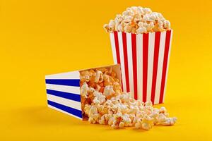 Glass with popcorn on a yellow background photo