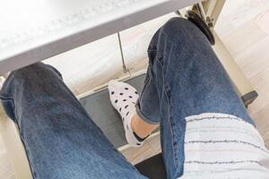 Female feet on the pedal of a sewing machine, motor photo