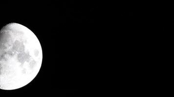Timelapse. A glowing huge moon as seen from earth through the atmosphere against a starry night sky. A large moon moves across the sky, the moon moving from the left frame to the right. video