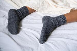 Woman wearing woolen socks and resting in bed. photo