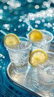 Closeup of three plastic cups with fizzy lemonade garnished with lemon slices on a tray photo