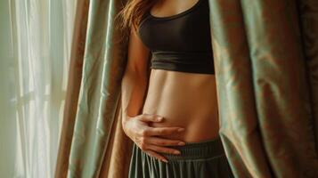Natural beauty, an unretouched, cropped portrait of a woman by a window, showcasing her exposed midriff photo