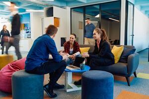 Multiethnic startup business team on meeting in a modern bright open space coworking office. Brainstorming, working on laptop. Group of coworkers walking around in motion blur photo