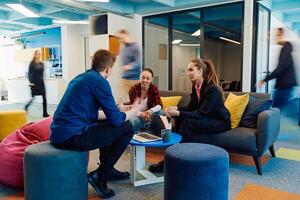 Multiethnic startup business team on meeting in a modern bright open space coworking office. Brainstorming, working on laptop. Group of coworkers walking around in motion blur photo