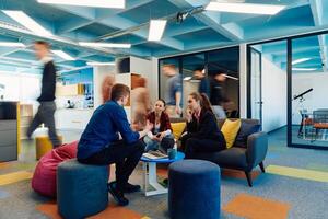 Multiethnic startup business team on meeting in a modern bright open space coworking office. Brainstorming, working on laptop. Group of coworkers walking around in motion blur photo