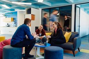 Multiethnic startup business team on meeting in a modern bright open space coworking office. Brainstorming, working on laptop. Group of coworkers walking around in motion blur photo