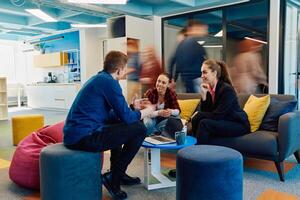 Multiethnic startup business team on meeting in a modern bright open space coworking office. Brainstorming, working on laptop. Group of coworkers walking around in motion blur photo