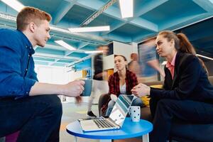 Multiethnic startup business team on meeting in a modern bright open space coworking office. Brainstorming, working on laptop. Group of coworkers walking around in motion blur photo