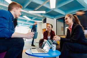 Multiethnic startup business team on meeting in a modern bright open space coworking office. Brainstorming, working on laptop. Group of coworkers walking around in motion blur photo