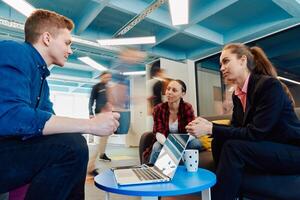 Multiethnic startup business team on meeting in a modern bright open space coworking office. Brainstorming, working on laptop. Group of coworkers walking around in motion blur photo