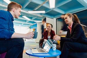 Multiethnic startup business team on meeting in a modern bright open space coworking office. Brainstorming, working on laptop. Group of coworkers walking around in motion blur photo