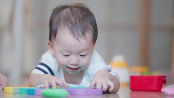 New born asian boy toddler playing with colorful wooden blocks on the floor with mother next to him, cute small child having fun with wooden toys smiling laughing at home living room, smart child video