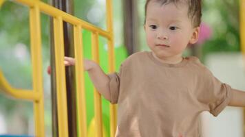 Healthy asian male toddler walking inside outdoors playground on beautiful sunny day, playing time, learning from playing for young children, child confidence self esteem, playing experiences video