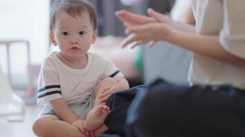 Asian mother teaches cute son playing with dry clay on the floor, carefree two generation family and cute small child having fun building tower laughing at home, play time, home sofa living room video