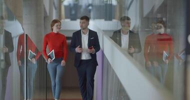 In the dynamic environment of a modern startup company, the director engages in a discussion with his young business colleague while they walk, reflecting the spirit of collaboration and innovation in video