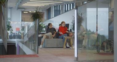 A businesswoman in a wheelchair in a modern company with her colleagues discussing behind her, symbolizing a workplace that values inclusivity, diversity, and collaborative discussions video