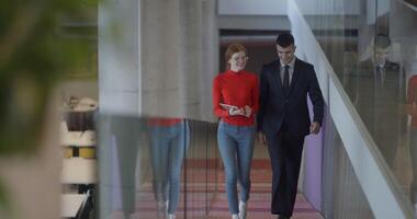 In the dynamic environment of a modern startup company, the director engages in a discussion with his young business colleague while they walk, reflecting the spirit of collaboration and innovation in video