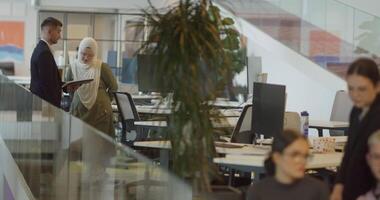 A diverse group of colleagues exchange business experiences, engage in collaborative problem-solving, and work together in a relaxed, modern office interior, demonstrating the value of teamwork and video