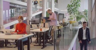 A director arrives at a large, modern office, where he joins his colleagues, exemplifying corporate leadership and teamwork in a dynamic workplace video